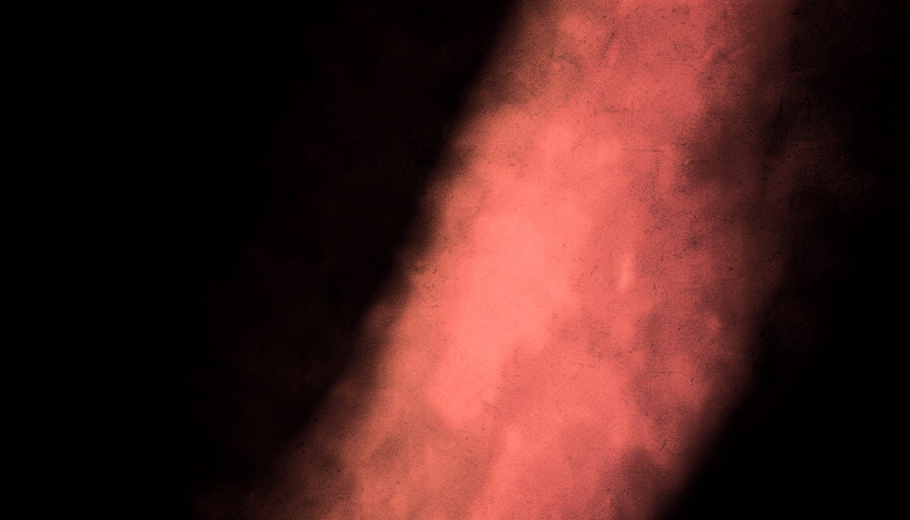 A duotone photograph in near-black and warm coral tones showing a minimal abstract texture with soft gradients
